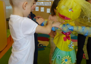 Dzieci naklejają różny materiał plastyczny na kukłę pani Wiosny.